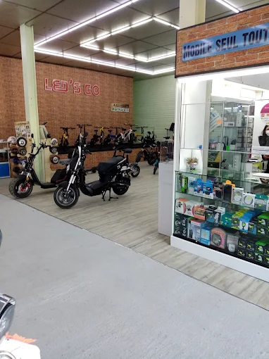 Espace commercial avec des deux-roues exposés et une vitrine remplie d’accessoires électroniques
