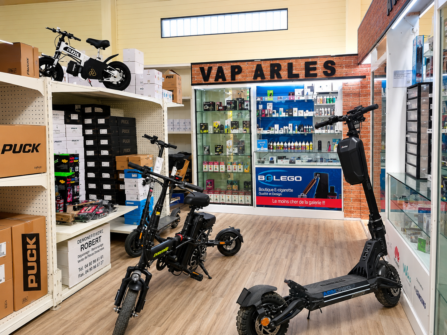Vélos et trottinettes exposés dans un espace commercial devant l’enseigne VAP ARLES